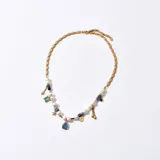 Gargantilla dorada con cadena de eslabones rectangulares, perlas blancas, cuentas azules y dijes colgantes con forma de estrella, gota y cubo.