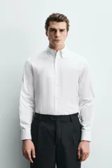 Camisa regular fit de algodón con diseño de rayas finas celestes y blancas. Cuenta con cuello abotonado, manga larga con puños abotonados y cierre frontal de botones.