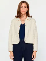 Chaqueta de algodón en color beige con diseño acolchado de costuras decorativas. Presenta cuello clásico, cierre frontal con botones metálicos y bolsillos frontales aplicados.