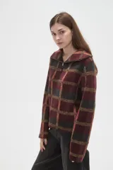 Sweater de tejido jacquard con diseño a cuadros en tonos bordó, negro y beige. Presenta un corte holgado, cuello solapa amplio y cierre frontal parcial con cremallera.