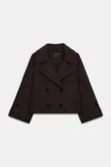 Trench corto de color marrón oscuro, con cuello de solapa, cierre frontal cruzado con botones y mangas tres cuartos con detalle de vuelta, trabilla y botón. Cuenta con bolsillos delanteros de vivo.