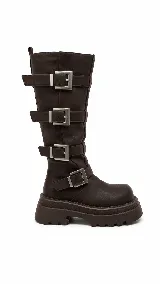 Botas biker marrones de caña alta, con suela chunky estriada y cuatro hebillas metálicas plateadas XL que se distribuyen a lo largo de la caña. Incluye cierre lateral interno.