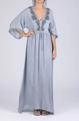 Vestido largo celeste con escote en V, mangas tres cuartos y bordado en el escote y puños.