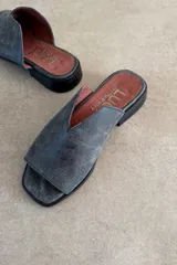 Sandalias chatitas de cuero vacuno color gris azulado, con diseño destalonado y capellada envolvente con abertura en V.