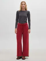 Pantalón de punto con textura tipo terciopelo, de corte ancho y holgado. Presenta cintura elástica con cordón de ajuste y detalle de pespuntes decorativos en los laterales.