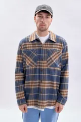 Sobrecamisa a cuadros en tonos azul marino, beige y marrón, con cierre frontal de botones, bolsillos con solapa en el pecho y mangas largas.