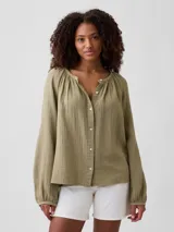 Camisa de muselina color verde militar, de manga larga abullonada, con cuello redondo fruncido y cierre frontal de botones.