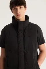Chaleco puffer negro con cuello alto y cierre frontal con botones a presión.