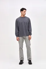 Remera de manga larga en color gris oscuro, confeccionada en algodón pesado con textura suave. Presenta un bolsillo frontal en el pecho con un pequeño bordado de la marca y puños elásticos en las mangas.