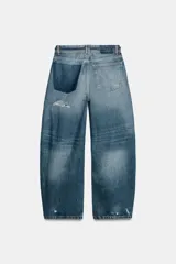 Jeans de tiro medio y corte baggy con cinco bolsillos, trabillas y rotos decorativos. Cuenta con detalle de cinturón confeccionado en el mismo tejido y cierre frontal con cremallera y botón metálico.