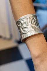 Brazalete ancho plateado con diseño labrado y acabado mate.