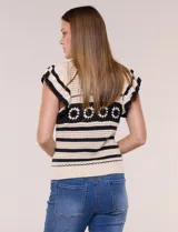 Buzo tejido en punto calado estilo crochet color beige con rayas horizontales negras y una franja central con motivos florales. Presenta cuello redondo, mangas cortas con volados y terminaciones en rib.