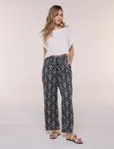 Pantalón wide leg de calce holgado y caída fluida, color negro con estampado de arabescos blancos. Cuenta con cintura elastizada fruncida con lazo ajustable, terminaciones en canutillo de madera y bolsillos laterales funcionales.