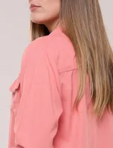 Camperita de lino liviana, marca Dash, con estampado botánico de hojas en tonos azules, verdes y tostados sobre base blanca. Presenta cierre frontal con botones, cuello clásico y bolsillos aplicados en el pecho.