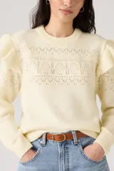 Sweater de punto color crema, con cuello redondo y calado en el frente, mangas largas con volados en los hombros y puños acanalados.