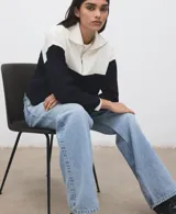 Jersey de punto de manga larga, con diseño bicolor en blanco y negro, cuello alto con cierre de cremallera corta.