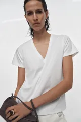 Mini bolso de mano confeccionado en piel, con asa corta, cierre de cremallera y solapa superior. Cuenta con bolsillos exteriores en la parte delantera y trasera, y un bolsillo interior con cierre.