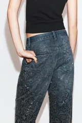 Jeans de tiro medio con corte baggy y cinco bolsillos. Presenta un diseño de estampado floral realizado con aplicaciones de strass a contraste sobre el tejido denim.