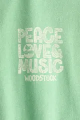 Remera oversized verde de punto de algodón, con hombros caídos, cuello redondo acanalado y estampa pequeña en el pecho con la frase 'Peace Love & Music Woodstock'.