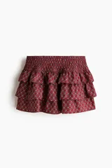 Short pollera de sarga en mezcla de viscosa con estampado geométrico en tonos bordó y blanco. Presenta cintura ancha fruncida y diseño escalonado con volados.