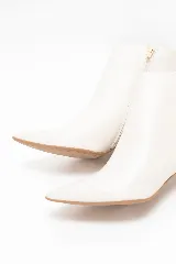 Bota corta de cuero color blanco off white, con taco fino de 6 cm y diseño en punta.