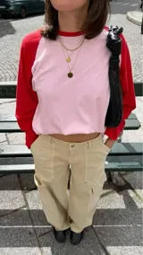 Remera oversize de algodón con diseño raglán, cuerpo en color rosado y mangas largas en color rojo, con cuello redondo rojo.