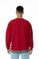 Buzo rojo de jersey doble 100% algodón, con corte levemente boxy y logo frontal serigrafiado en estilo graffiti. Costuras negras visibles y cuello redondo con ribete azul. Hecho en Uruguay.