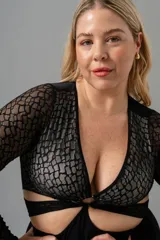 Body negro de encaje elastizado con mangas largas y transparencias. Busto forrado en LYCRA® color crudo, aro en el escote y broches en la entrepierna con fundillo de algodón.