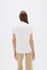 Blusa de viscosa color blanco, de corte holgado, con cuello en V y cierre frontal parcial de botones grandes con efecto carey.
