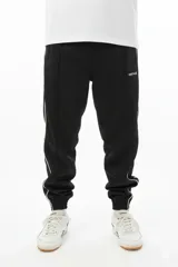 Pantalón de jogging negro con vivo lateral doble blanco, corte holgado, tiro medio, botamanga elastizada y cierres en los tobillos.
