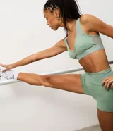 Top deportivo de microfibra color verde menta, con diseño de escote en V, banda elástica inferior ancha y detalles de tul en los breteles y laterales. Cuenta con copas estructuradas para mayor soporte.