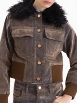 Campera estilo bomber de silueta entallada, confeccionada en tela Denim Velvet con acabado visual de jean y tacto de terciopelo. Presenta cuello desmontable de pelo sintético, cierre frontal con botones, bolsillos superiores y puños y cintura de tejido elástico acanalado.