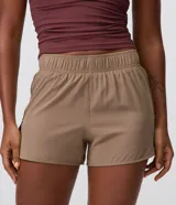 Bermuda deportiva Get Over modelo runner color beige, con cintura elástica, bajo redondeado y aberturas laterales. Cuenta con un pequeño bolsillo funcional trasero.