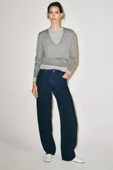 Jeans de tiro medio con diseño de perneras curvas y corte recto, confeccionados en denim con estampado paisley en tonos marrones y beige. Presentan diseño clásico de cinco bolsillos, trabillas para cinturón y cierre frontal con cremallera y botón metálico.