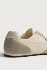 Zapatilla estilo retro de cordones, con parte superior en combinación de piezas textiles y detalles de piel, en tonos beige y gris con suela a tono.
