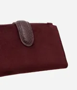 Billetera tipo sobre de Satinato, confeccionada en material sintético efecto gamuza color bordó. Presenta un cierre principal con tirador metálico circular grabado y una solapa central con textura tipo reptil.