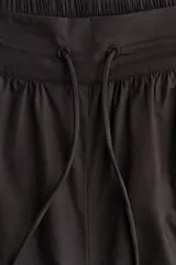 Pantalón de popelina de algodón negro, de corte ancho y silueta globo con cordón ajustable en los bajos y en la cintura elástica.