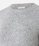 Suéter de punto jaspeado en color gris oscuro, con cuello redondo y mangas largas. Presenta un diseño integrado con una camisa blanca debajo, creando un efecto de capas superpuestas.
