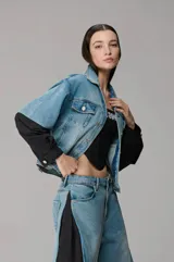 Chaqueta de denim con recortes de nylon negro en las mangas, diseño estructurado de estilo urbano con cierre frontal de botones metálicos y bolsillos con solapa en el pecho.