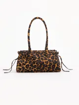 Cartera de hombro de cuero vacuno con pelo y estampado animal print de leopardo. Cuenta con herraje metálico tipo lock con llave colgante, asas largas y tiras laterales ajustables.