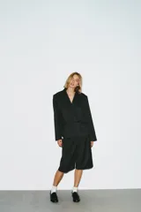 Blazer corto de corte oversize con estampado de cuadros, cuello con solapas de muesca y manga larga. Presenta cierre frontal cruzado con un botón y falsos bolsillos de vivo en el delantero. Incluye forro interior.