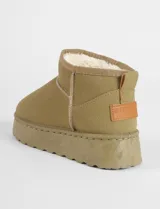 Botas cortas tipo ugg color beige, con interior forrado en corderito sintético y suela de plataforma plana.
