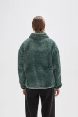 Buzo de textura afelpada con diseño de rayas horizontales finas en tonos marrones. Presenta cuello alto con cierre frontal parcial y mangas largas holgadas.