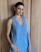 Vestido largo de denim azul, con escote en V, sin mangas, corte holgado, bolsillos laterales y aberturas en los costados de la falda.