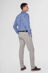 Pantalón de gabardina color marrón claro, corte slim fit, con bolsillos laterales y traseros. Se ajusta a la cintura con cinturón de cuero marrón.
