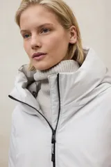 Campera larga acolchada color verde oliva, con capucha grande y cierre frontal de cremallera negra.