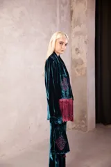 Cartera de mano tipo bolsa confeccionada en terciopelo de seda color violeta, con bordado floral en hilo dorado y detalle de borlas colgantes.