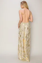 Vestido largo de tirantes finos con escote en V, confeccionado en tela fluida con estampado metalizado en tonos dorados y plateados. Presenta un diseño de corte recto y espalda descubierta.