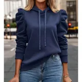 Buzo tipo hoodie de color azul marino, confeccionado en tejido suave con diseño de mangas princesa fruncidas en los hombros. Presenta capucha con cordones ajustables y puños elásticos.