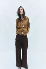 Camisa marrón a rayas con cuello redondo, mangas largas anchas y puños rectos. Cuenta con cierre frontal de botones y un lazo cinturón ajustable del mismo tejido en la cintura.